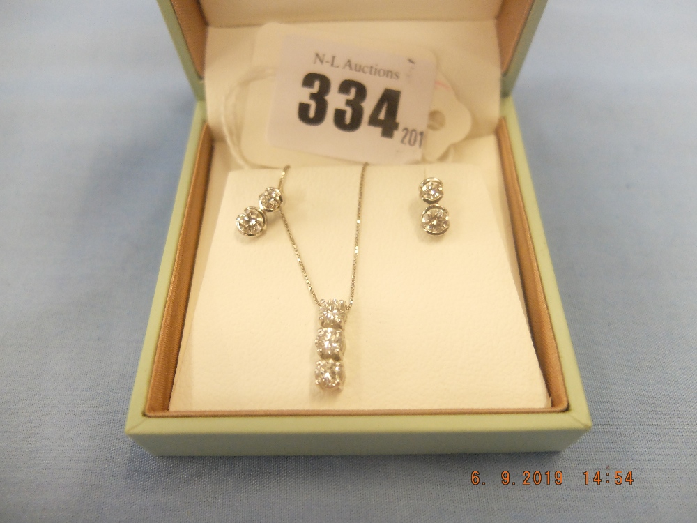 A pair of 18ct white gold and diamond earrings plus a matching pendant on white gold chain (9ct