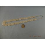 A bone necklace and a loose cameo