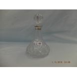 A cut glass decanter with silver collar