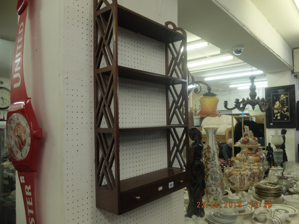 A mahogany hanging wall shelf with drawer beneath