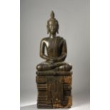 Buddha assis en virasana sur un haut socle à base lotiforme d'où pend une [...]