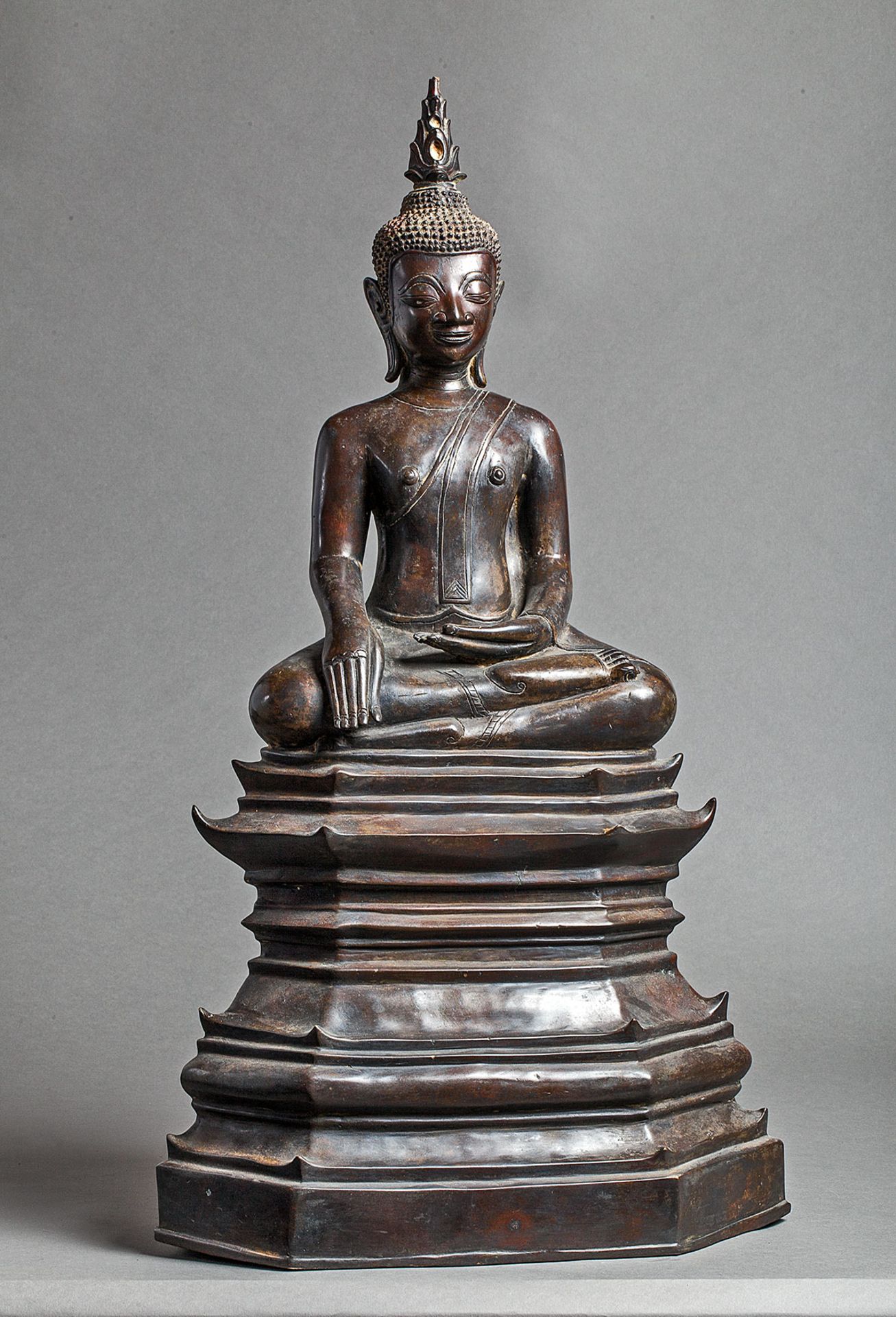 Buddha Maravijaya assis sur un haut socle étagé, les jambes en virasana et la main [...]