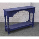 A painted blue pine two tier side table with carved decoration, 76cm x 106cm x 31cm.