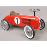 A child's tin ride on toy car modelled as a vintage racing car with working steering.
