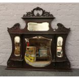 A carved mahogany empire cabinet top / over mantle mirror with bevel edge glass.