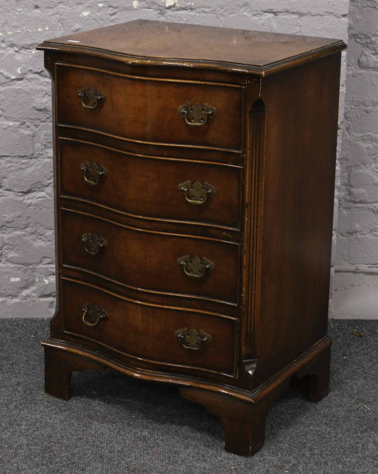 A miniature burr walnut chest of four serpentine drawers, cross banded in mahogany and raised on