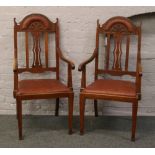 A pair of carved mahogany armchairs with leatherette and studded upholstery.