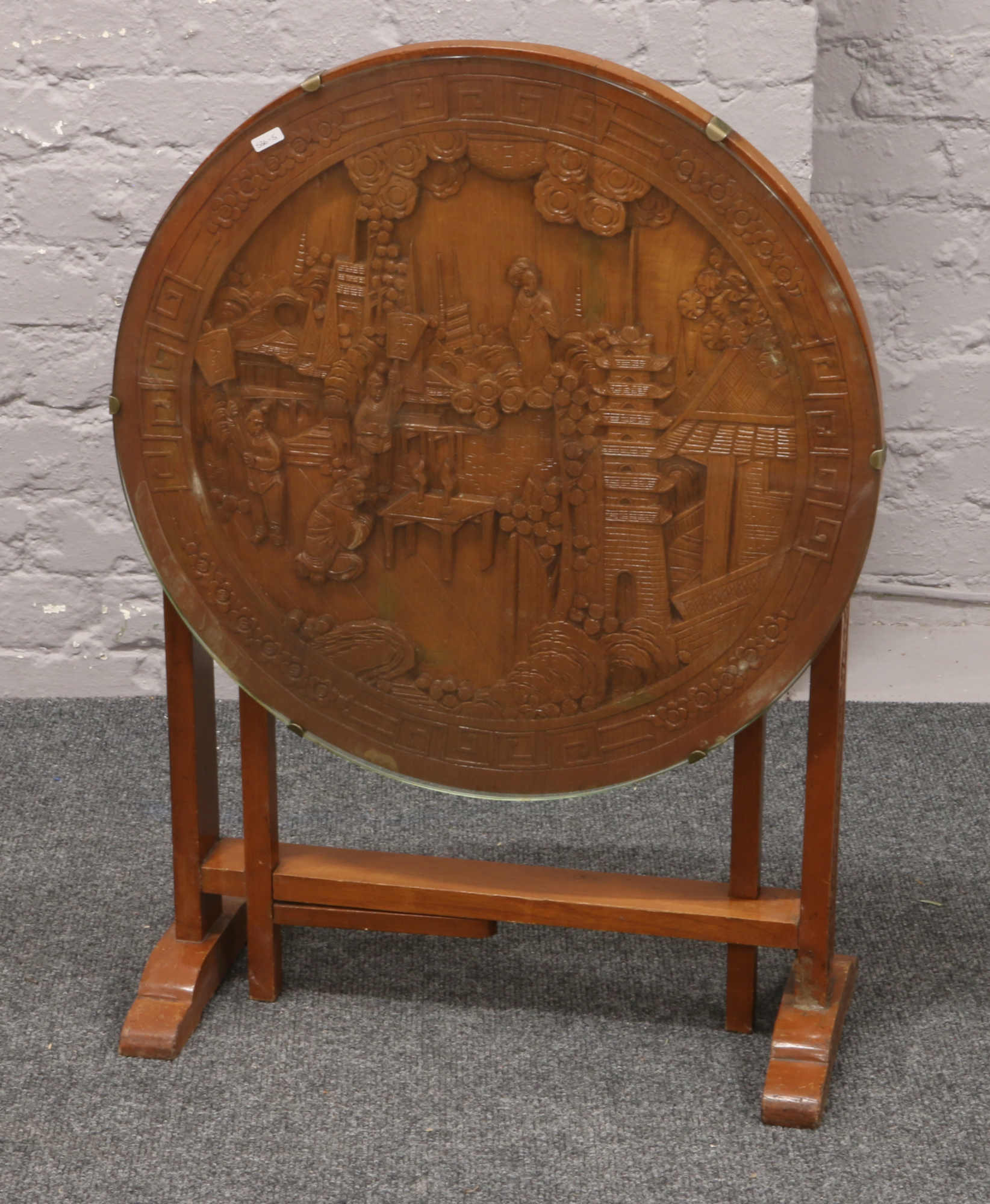 An oriental carved tilt top occasional table with glass top raised on gate leg supports.