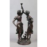 A late 19th century figural bronze formed as two maidens one holding a torch aloft raised on a