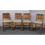 A set of four Ercol oak dining chairs with carved and panelled backrest.