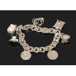 A silver charm bracelet with a 3 pence coin, St. Christopher and beetle locket.