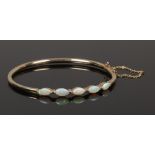 A boxed 9ct gold bangle set with five navette shaped opals.