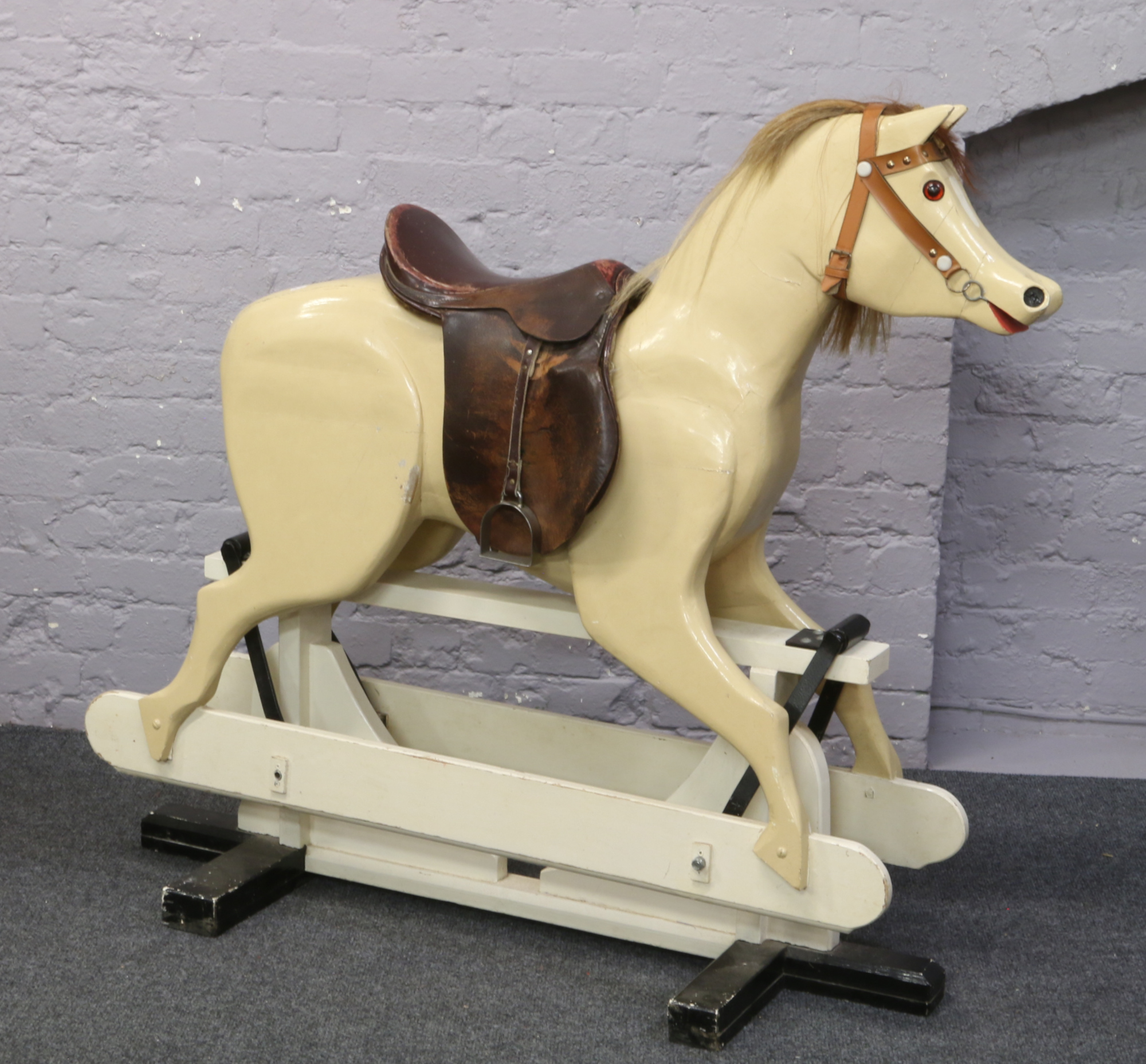 A large rocking horse painted cream with leather saddle, 118cm tall, 133cm length.