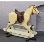 A large rocking horse painted cream with leather saddle, 118cm tall, 133cm length.