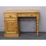 A pine desk with single drawer and cupboard.