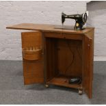A Singer treadle sewing machine housed in oak cabinet.
