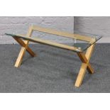 An X frame coffee table with bevel edge toughened glass top.