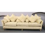 A Knoll sofa upholstered in cream floral design material and raised on brass castered legs, 270cm