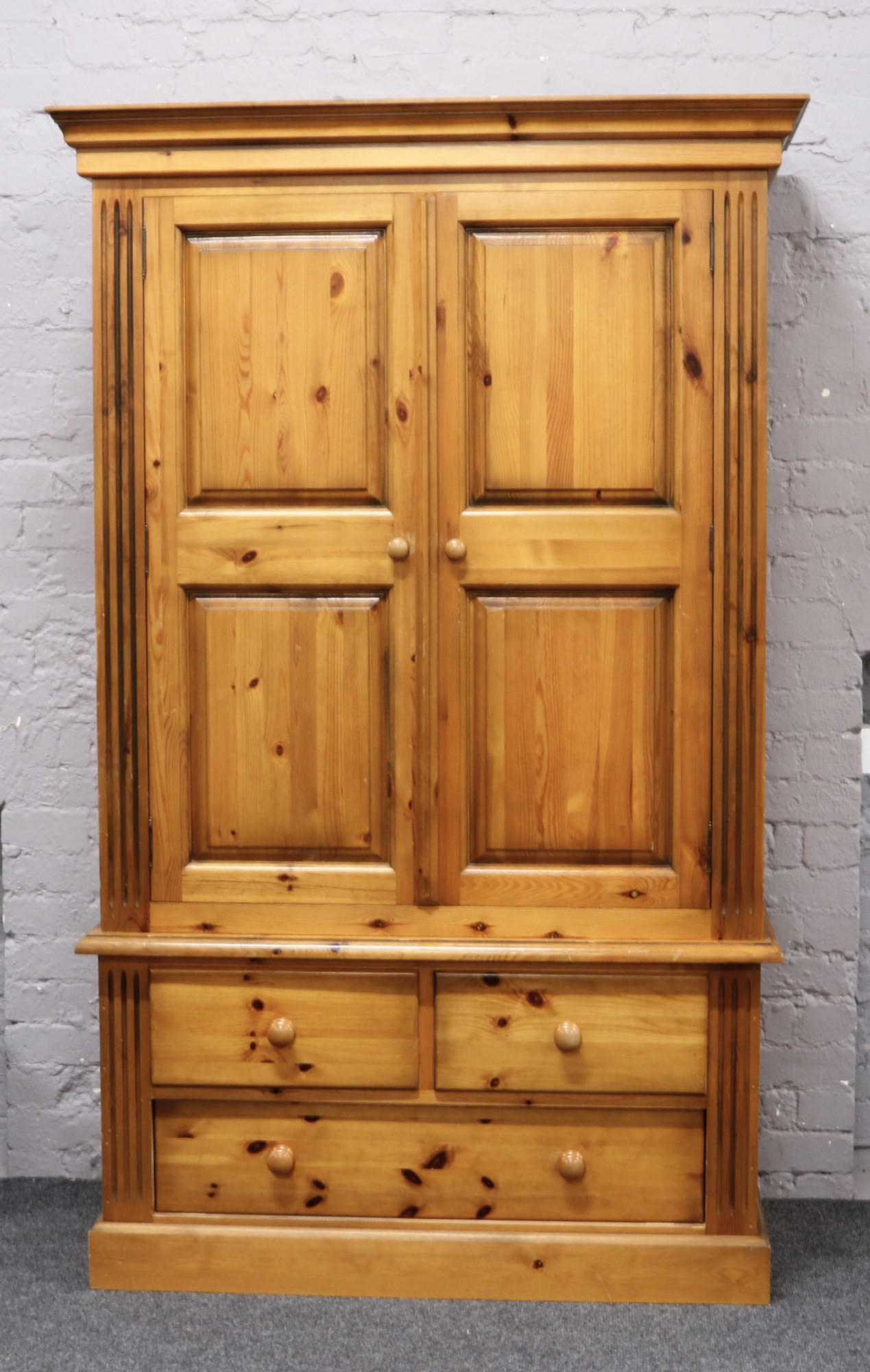 A large pine wardrobe with drawer base H 204cm W 127cm D 64cm.