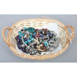 A basket of modern costume jewellery to include simulated pearls, beads, yellow metal locket etc.