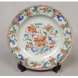 An 18th century Chinese plate. Painted in coloured enamels with flowers under a lambrequin border,