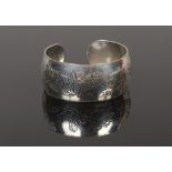 A silver christening bangle, decorated in relief with birds and their young on oak branches.