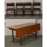 A single drop leaf teak dining table and four teak dining chairs.