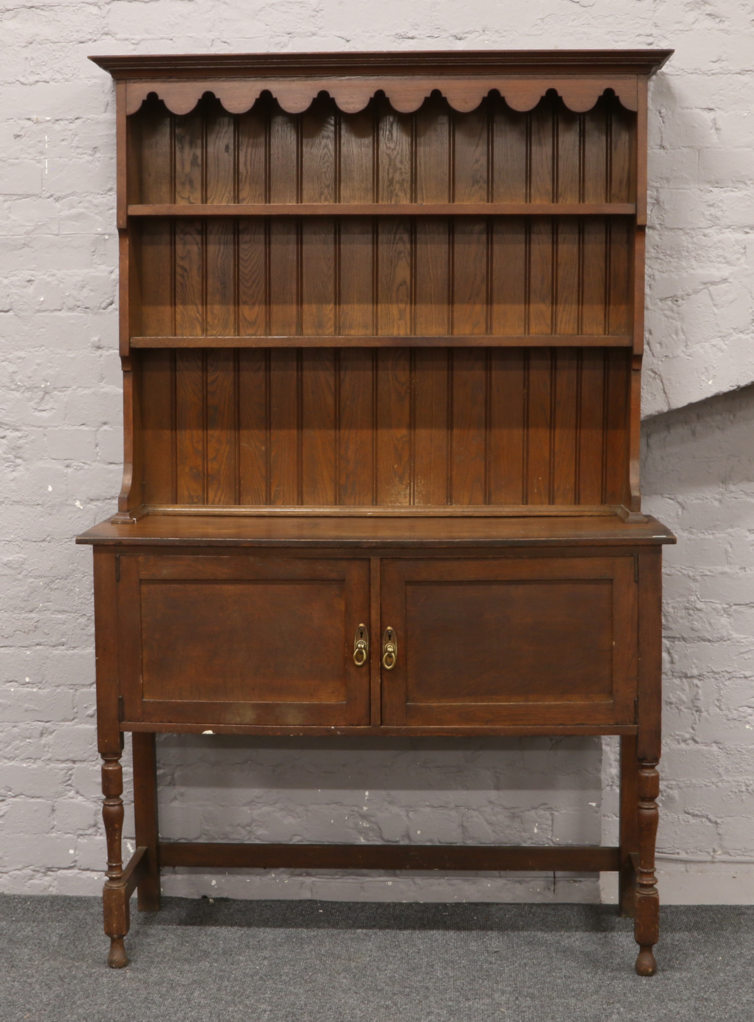 An oak dresser raised on turned supports.