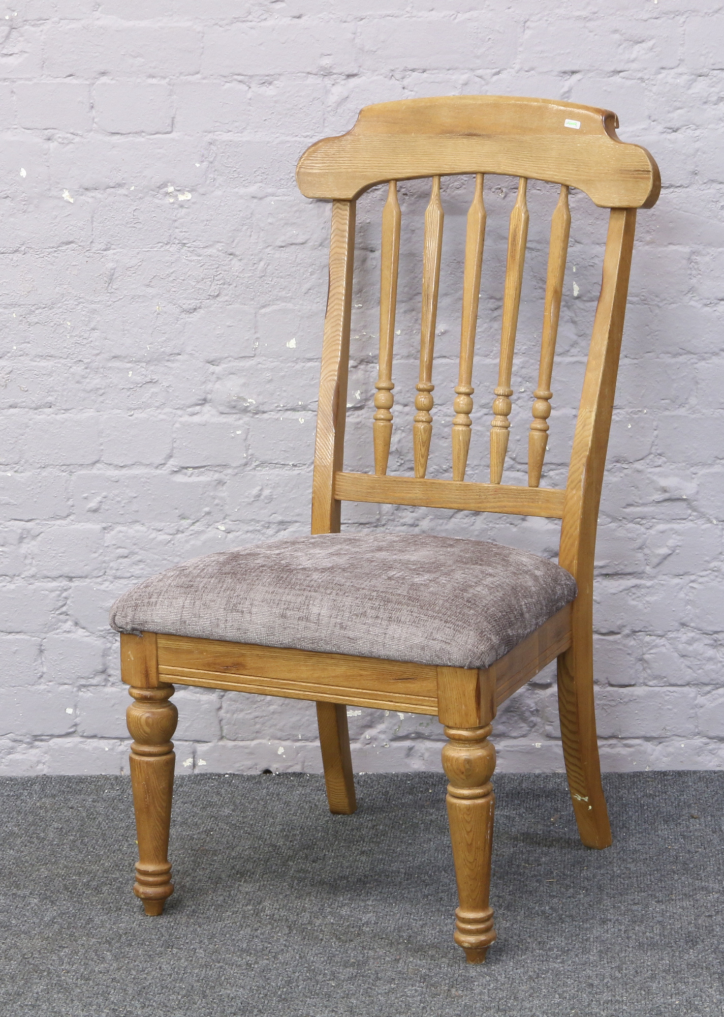 A light oak spindle back chair with upholstered seat.