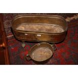 An oval brass planter raised on lion paw feet, along with a two handled brass planter.