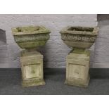 A pair of ornate cast concrete square formed pedestal planters decorated with roses and horses