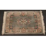 A Chinese teal ground wool rug decorated with flowers, 120cm x 180cm.
