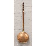 A Victorian copper bed warmer with later turned wood handle.