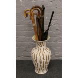 A large vase with contents of various walking sticks.