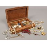 A carved hardwood jewellery box and contents of costume jewellery including yellow metal brooches,