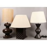 Three modern table lamps; two with pottery bases, along with a wooden example with checker board