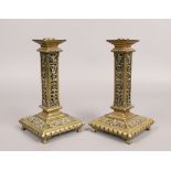 A pair of ornate pierced brass candle sticks of column form, raised on 4 small feet