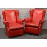 A pair of red leather wing back arm chairs with studded decoration.