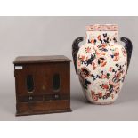 A vintage oak counter top vending machine (no key), along with a twin handled vase decorated in a