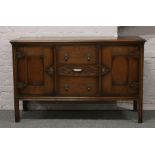 An Edwardian carved and panelled oak sideboard raised on square cut legs.