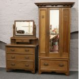 A carved oak Arts and Crafts three part bedroom suite; consisting of mirror front wardrobe, matching