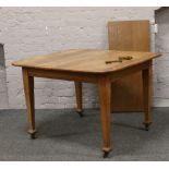 An Edwardian wind out dining table, with extra leaf and winding handle, raised on square cut