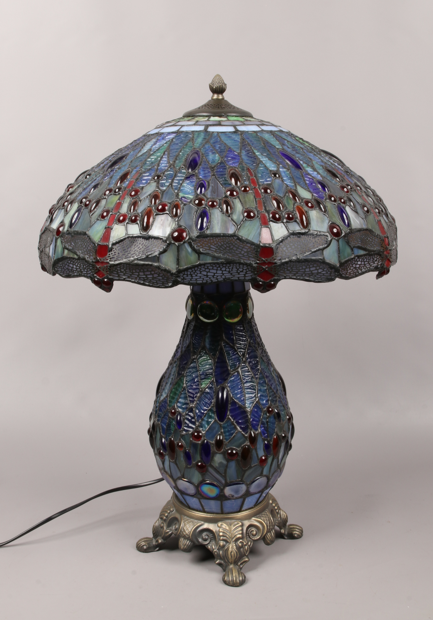 A large Tiffany style dragonfly table lamp with illuminating baluster shape base, raised on a bronze