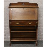 A carved oak Arts and Crafts bureau bookcase with fitted interior and brass metal mounts.