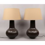 A pair of glazed pottery table lamps of baluster form with reeded decoration and coffee cream