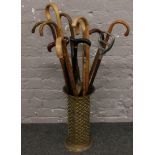 A brass stick stand with contents of walking sticks to include curved handle examples etc.