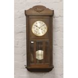 An Edwardian oak cased spring driven wall clock chiming on a coiled gong with pendulum and key.