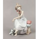 A Lladro figurine of a seated girl on the telephone.