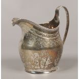 A George III silver cream jug with scrollwork engraving and reeded decoration to the rim and