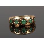 A 9ct gold five stone gypsy ring set with emeralds, size L.